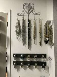 A heart-shaped jewelry hanger holds necklaces above a bracelet holder on the bottom.
