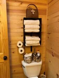 Towel rack and amenities baskets in this rustic, raw wood bathroom.