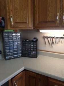 Organized tools with upper and lower brown cabinets, and plastic compartments with small parts.