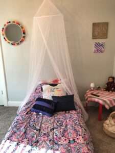 Pink and purple twin size bed with a white canopy hanging over it.