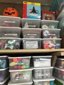 Holiday storage organizing in plastic bins on shelves.