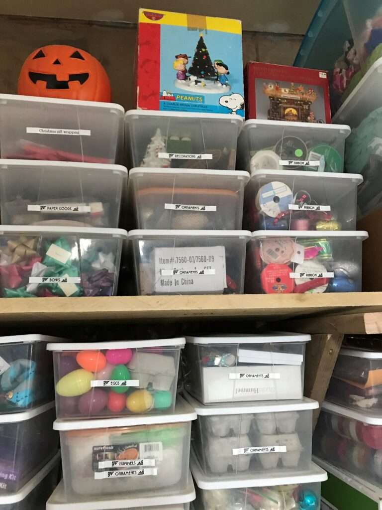 Holiday storage organizing in plastic bins on shelves.