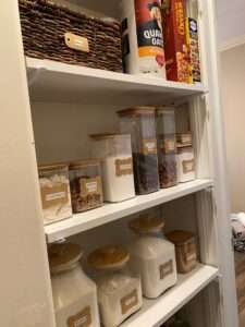 Dry goods, brown sugar, sugar, flour, etc, are stored in some glass and plastic containers in this kitchen pantry organization.