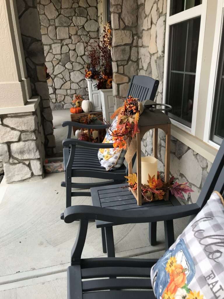 An outdoor fall arrangement on a porch with pumpkins and leaves.