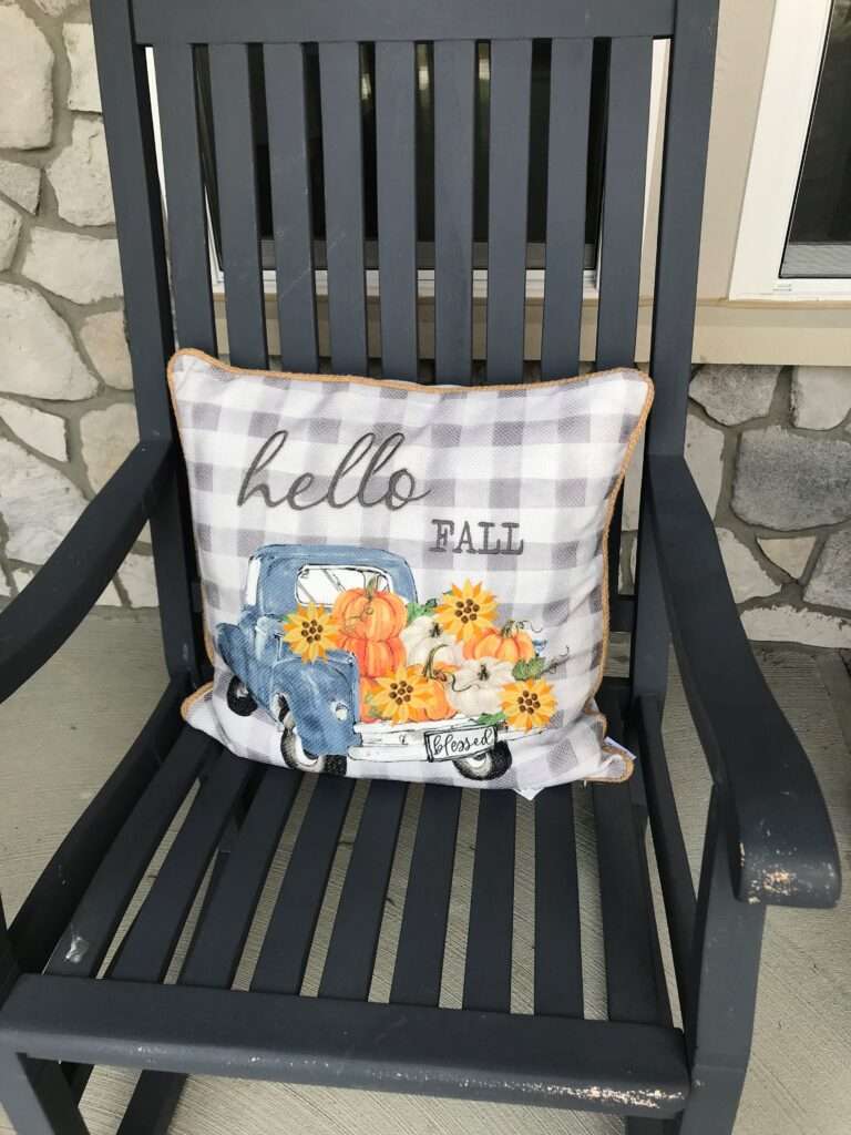 A pillow on a chair that says hello fall.