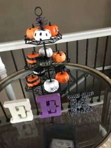Eek! in wooden letters next to decorated pumpkins on a spider web display.