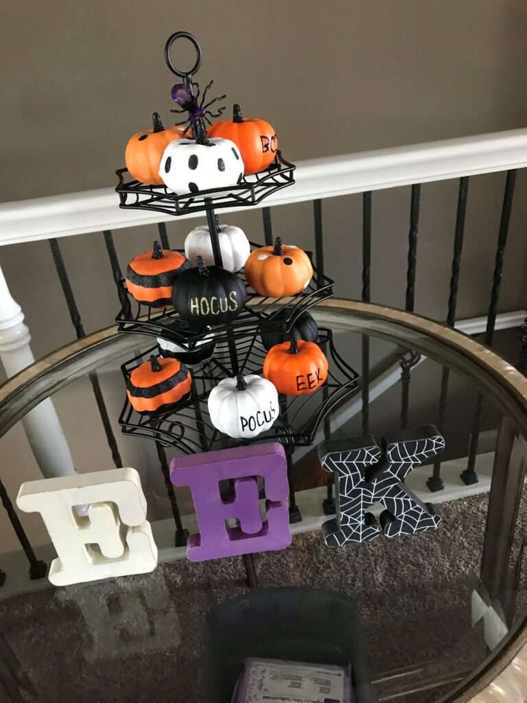 Eek! in wooden letters next to decorated pumpkins on a spider web display.