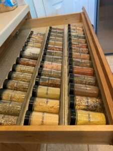 Spices well organized in matching containers in a drawer in the kitchen area.