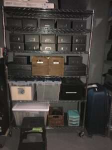Organized record and photo storage in black cardboard bins in the basement.