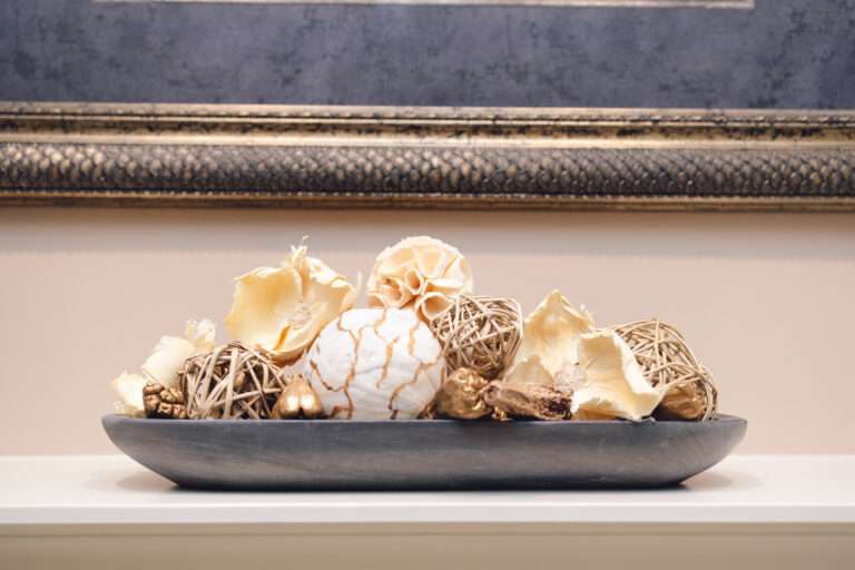 An up-close picture of the mantle center piece, with many neutral, round, textured, natural objects, sitting in a blue colored trench bowl.