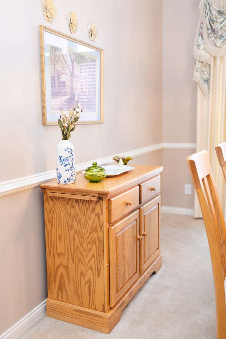 A side table with a blue and white floral vase, a small green glass dish, and white serving tray with white pear handles.