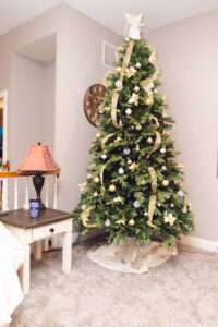A green Christmas tree with a white angel on top, gold ribbons flowing down, and gold and white ornaments.