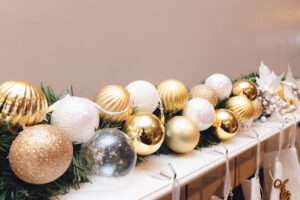 A mantle with some greenery, an abundance of gold, white, and clear ornaments.