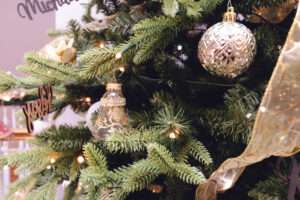 Close up of a green Christmas tree with gold ribbons flowing down, and gold and white ornaments.