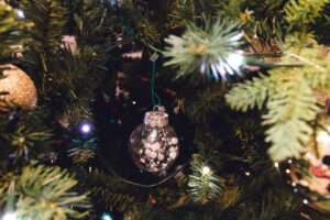 Close up of a green Christmas tree with gold ribbons flowing down, and gold and white ornaments.
